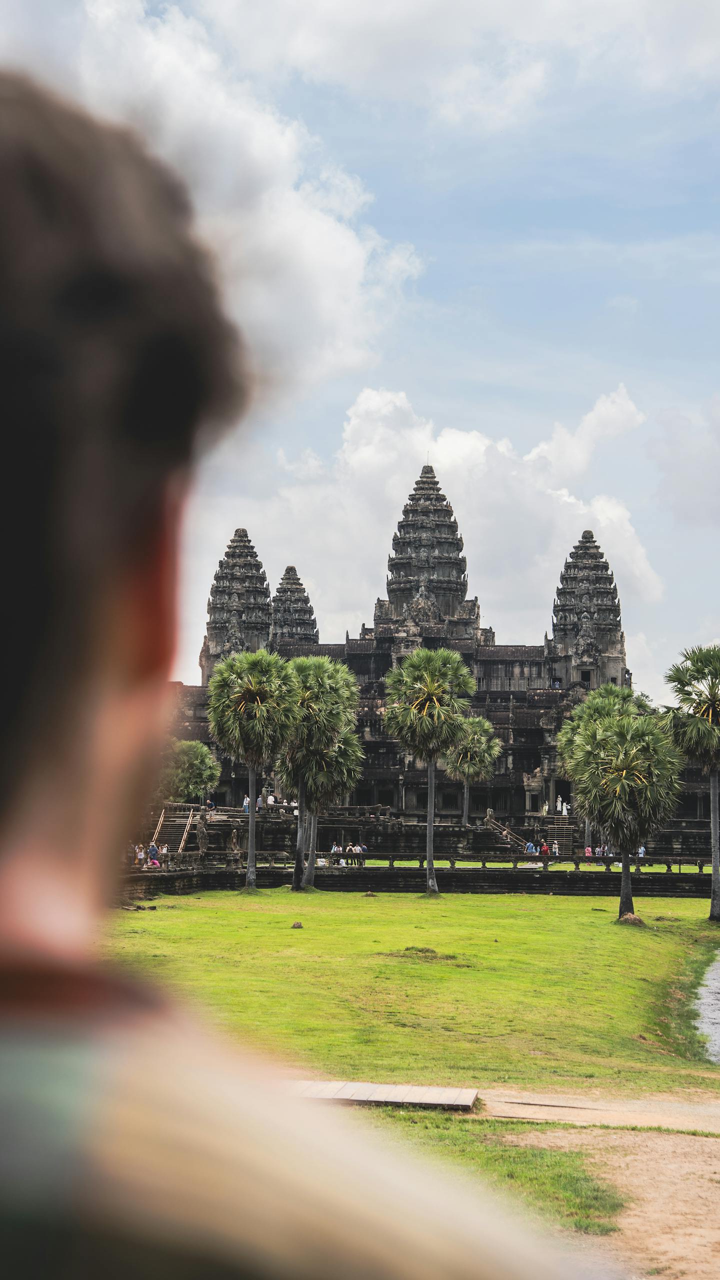 A person looks at the iconic Angkor Wat temple, showcasing its historic architecture.