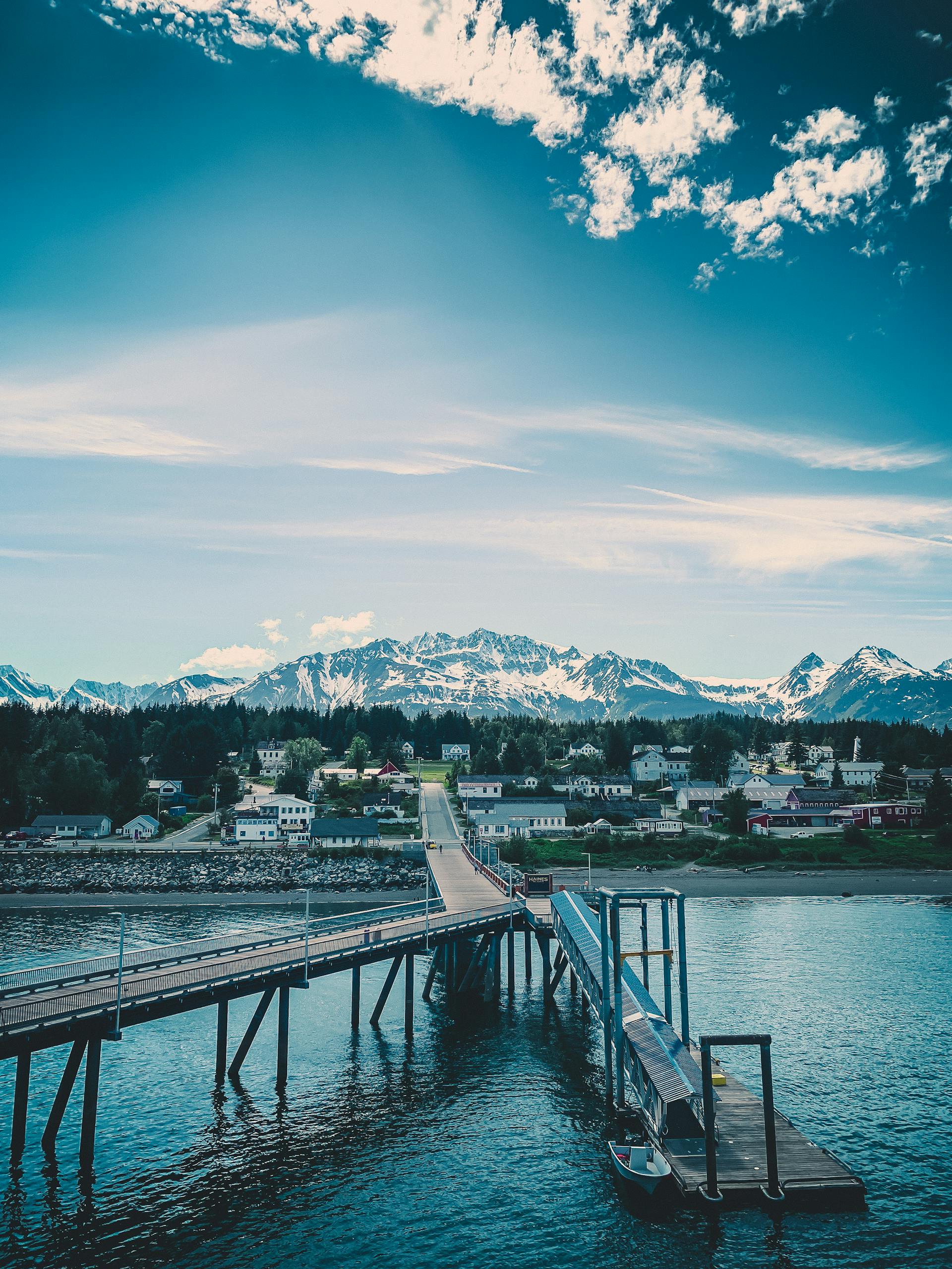 A picturesque view of Haines, Alaska with snowy mountains and a wooden pier, perfect for travel inspiration.