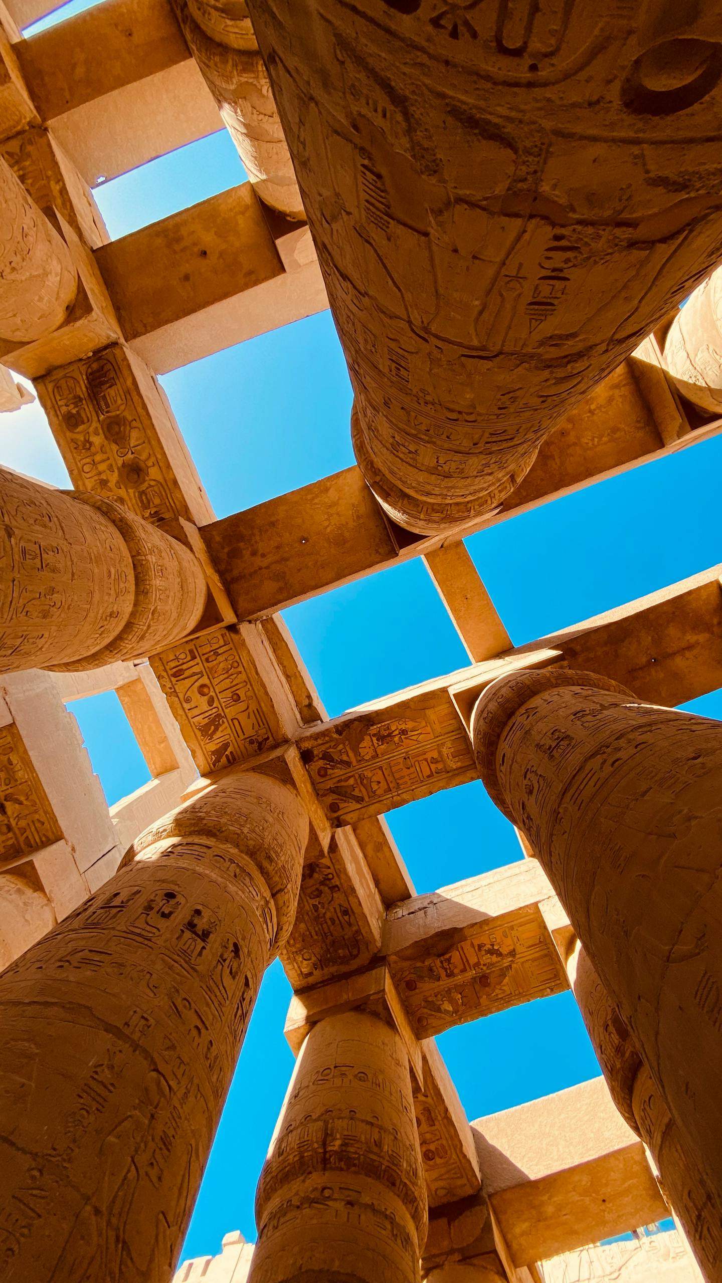 An upward view of the ancient hieroglyph-covered pillars at the Karnak Temple in Luxor, Egypt.