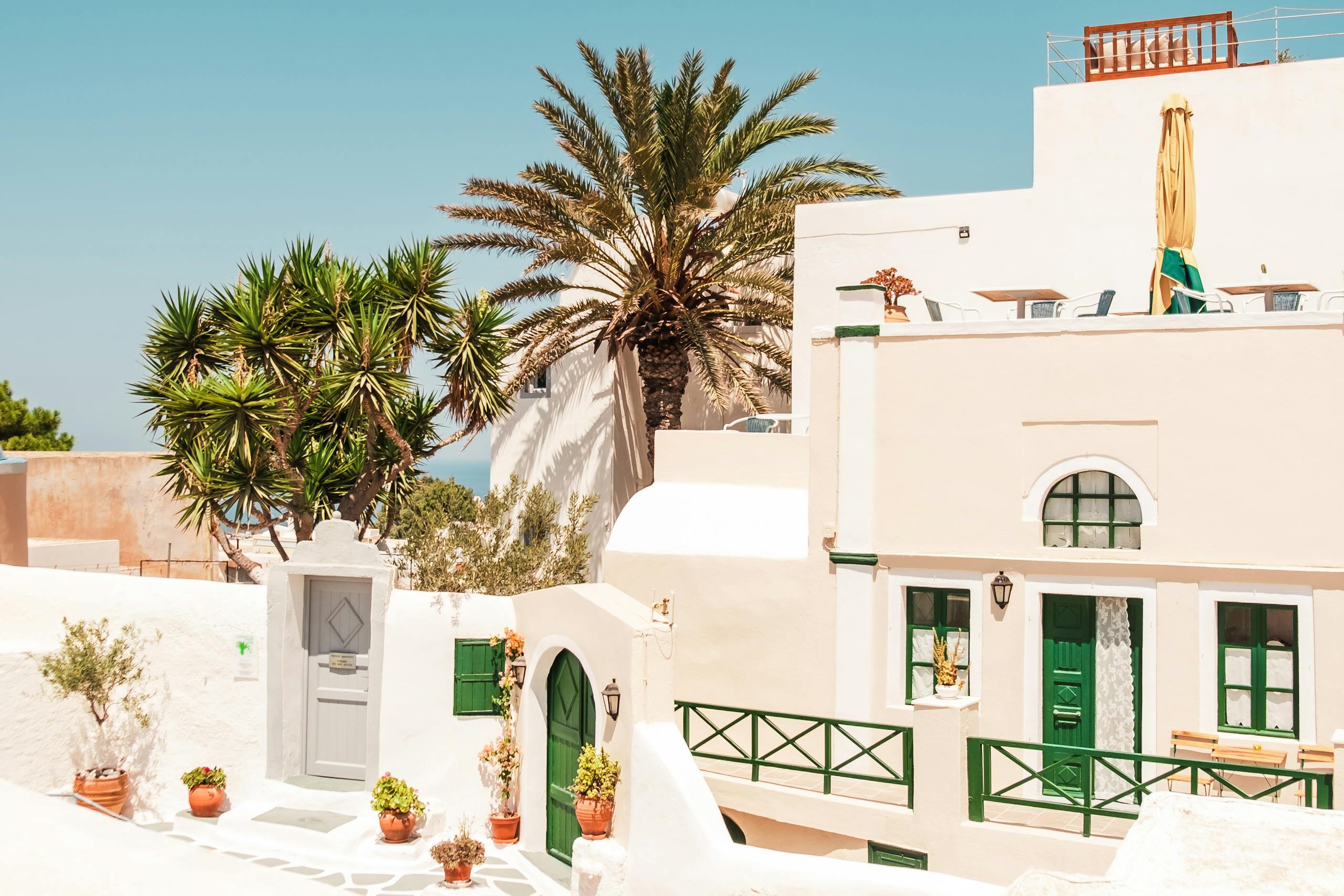 Charming Mediterranean style building with palm trees under a clear blue sky, perfect for travel inspiration.