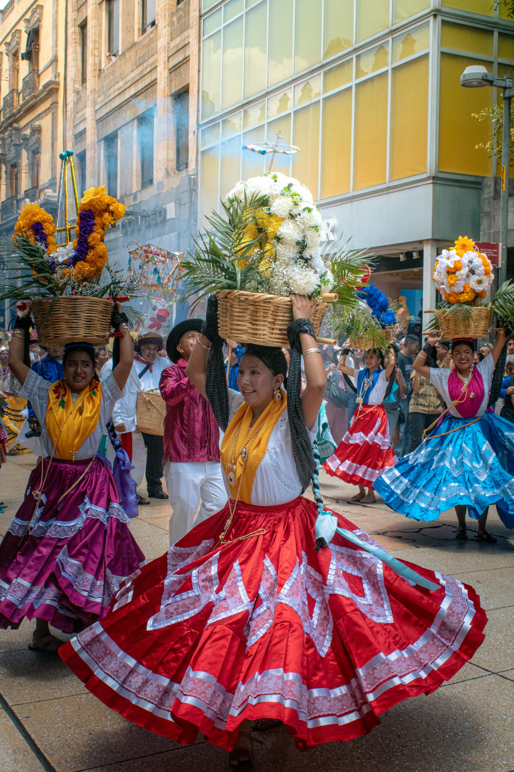Dancers in colorful traditional dresses participate in a lively festival parade in Oaxaca, Mexico.