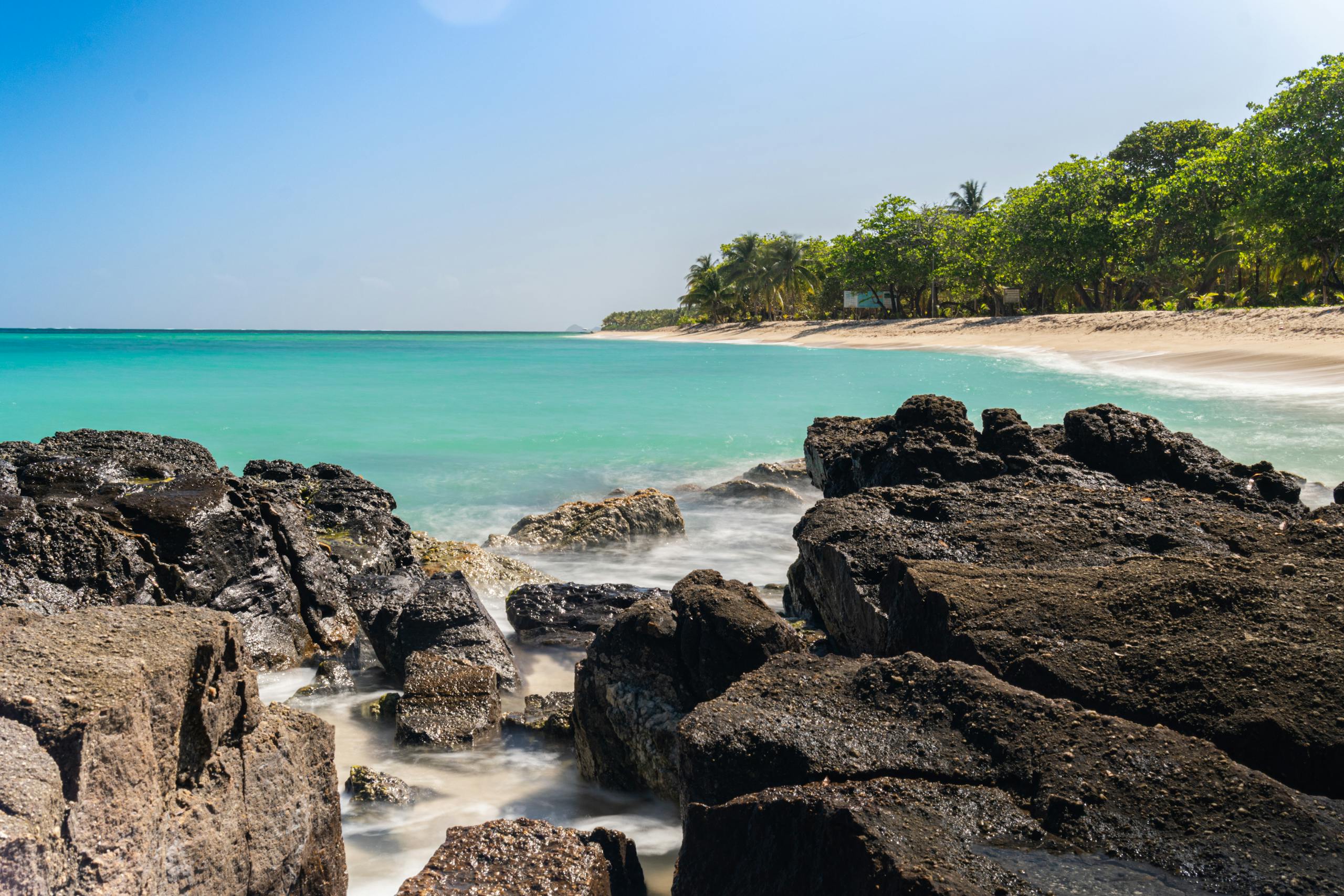 Experience the tranquil beauty of a tropical beach in Honduras with black volcanic rocks and turquoise waters.