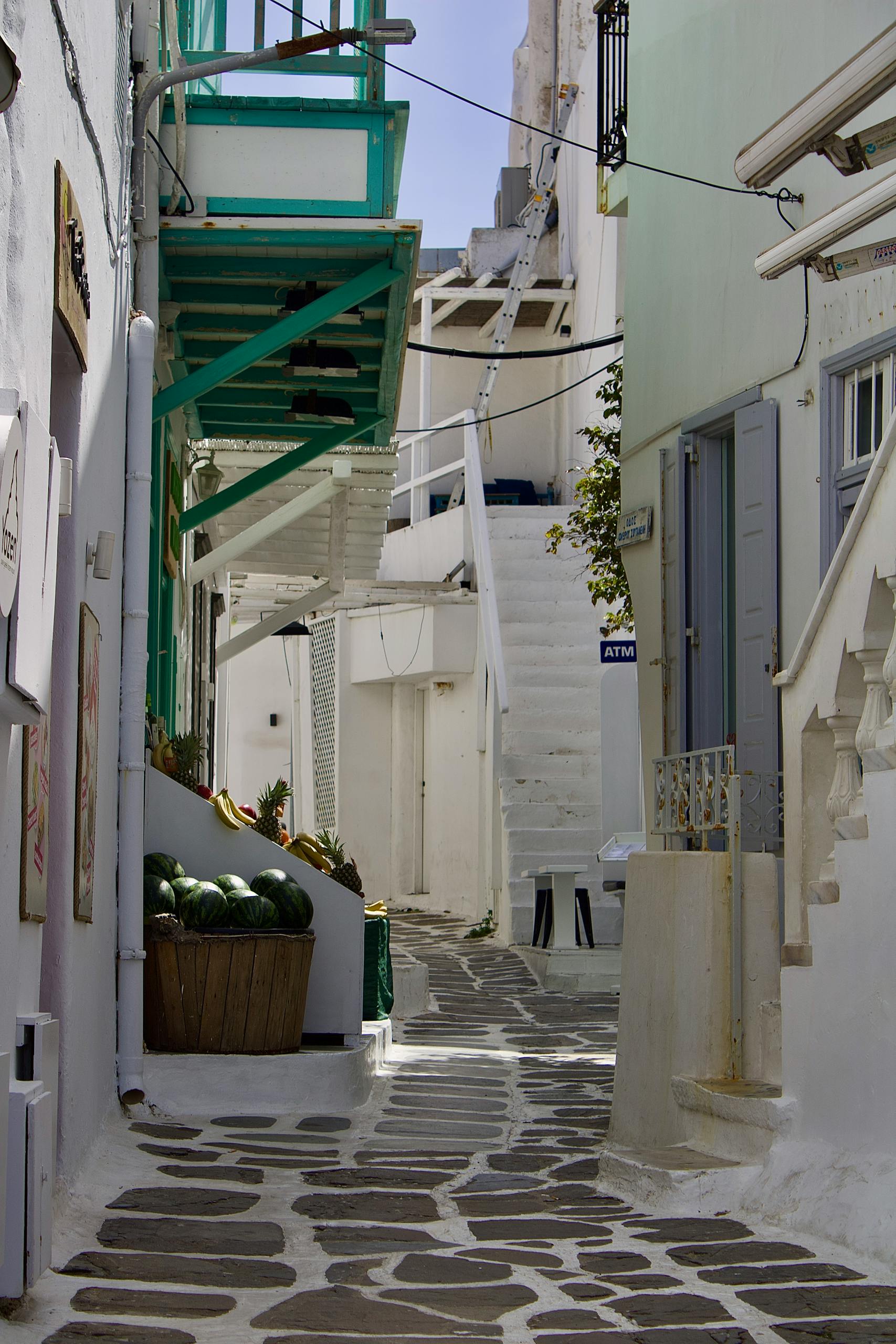 Explore a picturesque alley in Mykonos featuring iconic whitewashed buildings and vibrant accents.