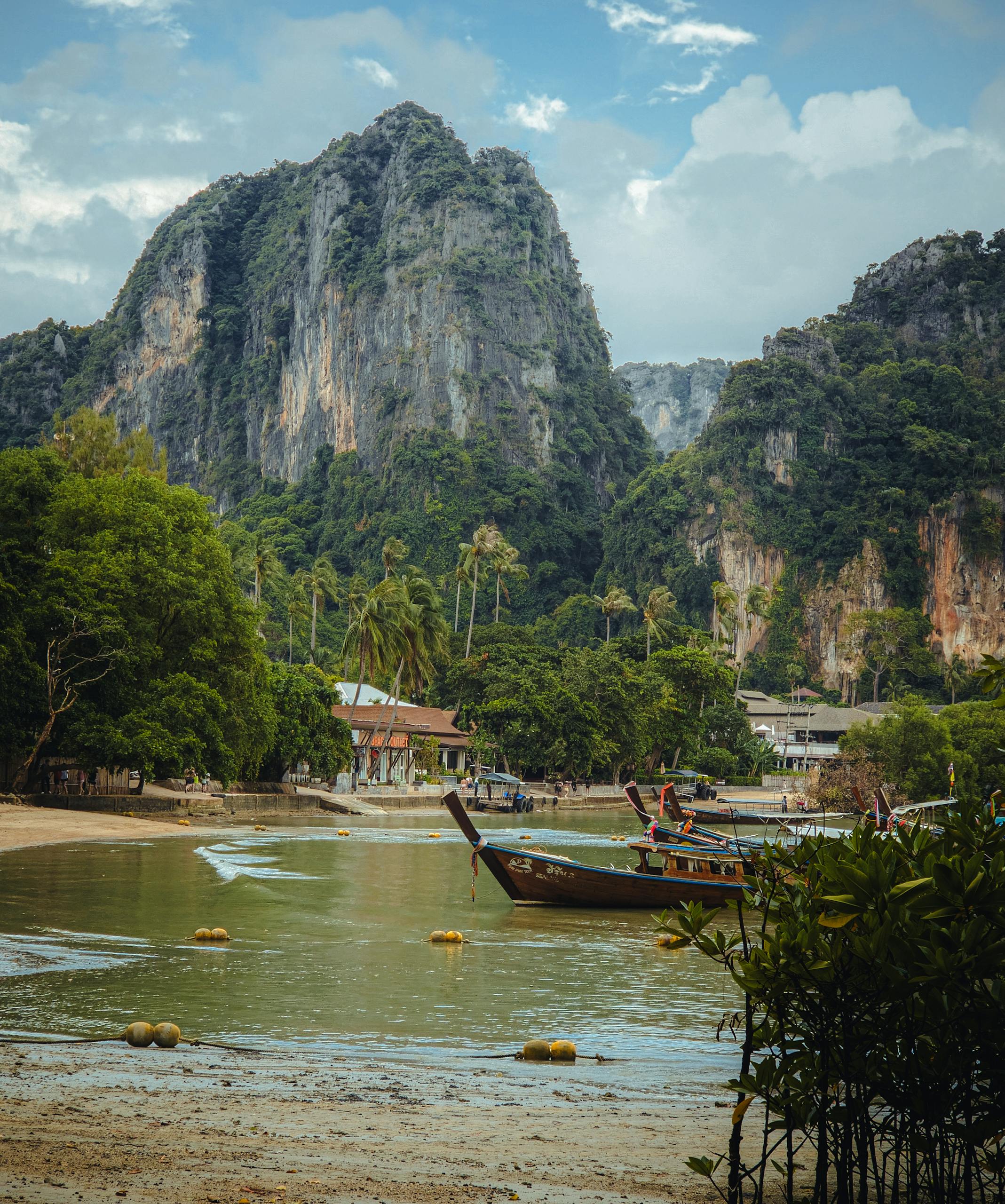 Explore the stunning cliffs and serene beaches of Krabi, Thailand, with traditional longtail boats in view.