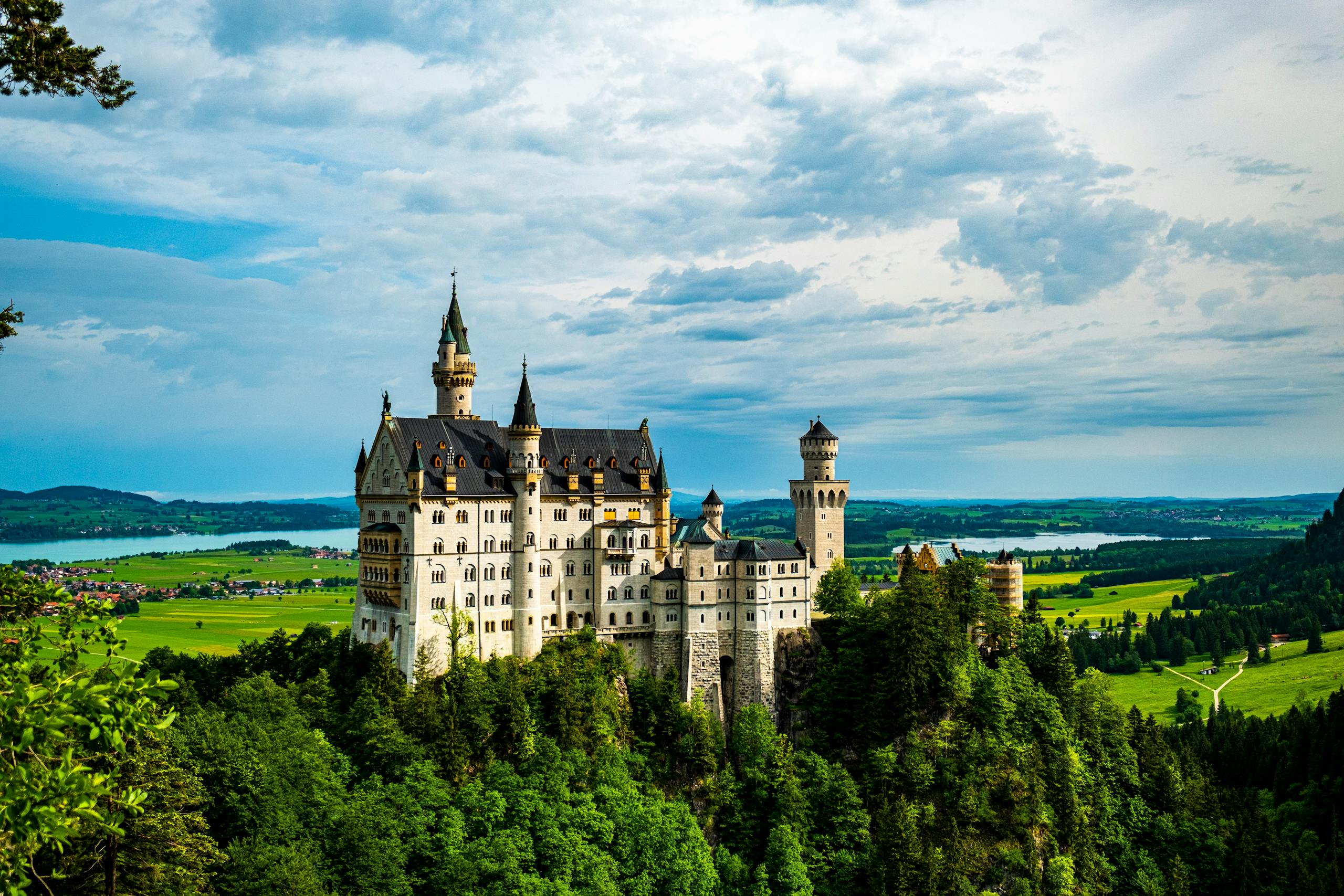 Magnificent view of Neuschwanstein Castle surrounded by lush greenery and expansive sky.