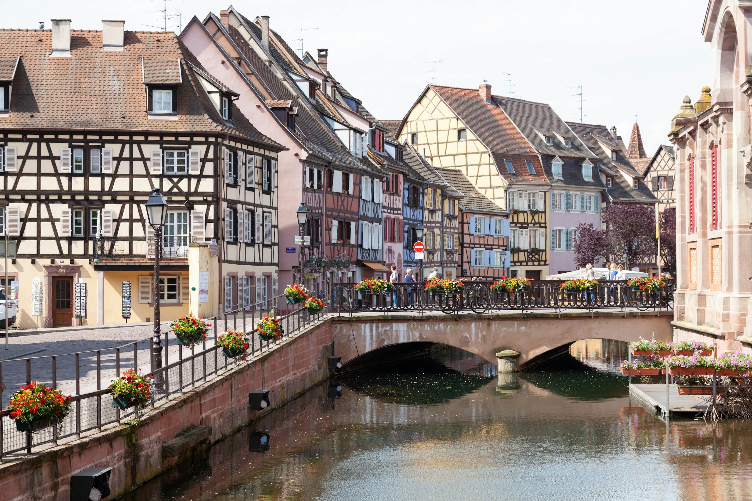 Scenic view of Colmar's half-timbered houses and picturesque bridge over a peaceful canal.