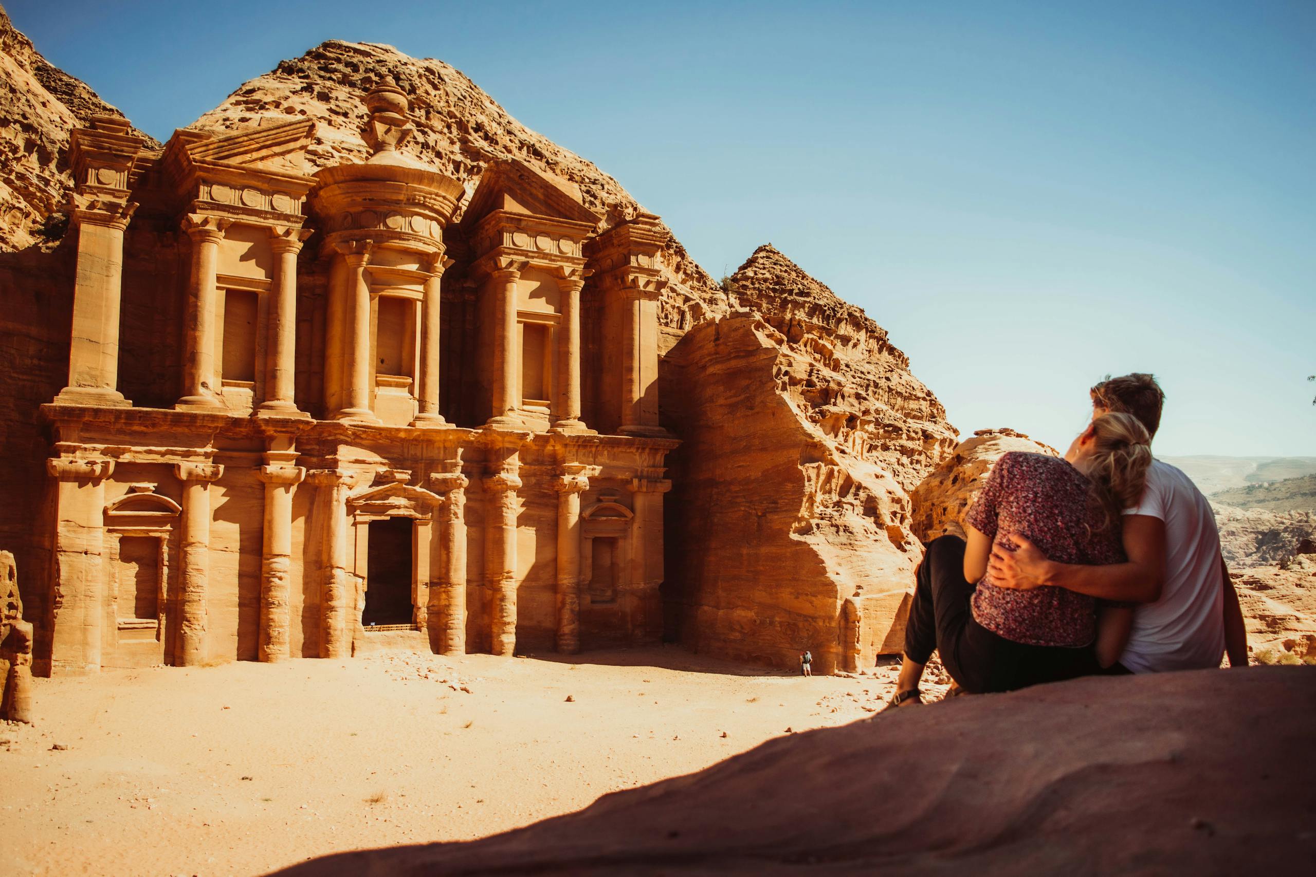 A couple embracing outdoors at Petra's historic Monastery in Jordan.