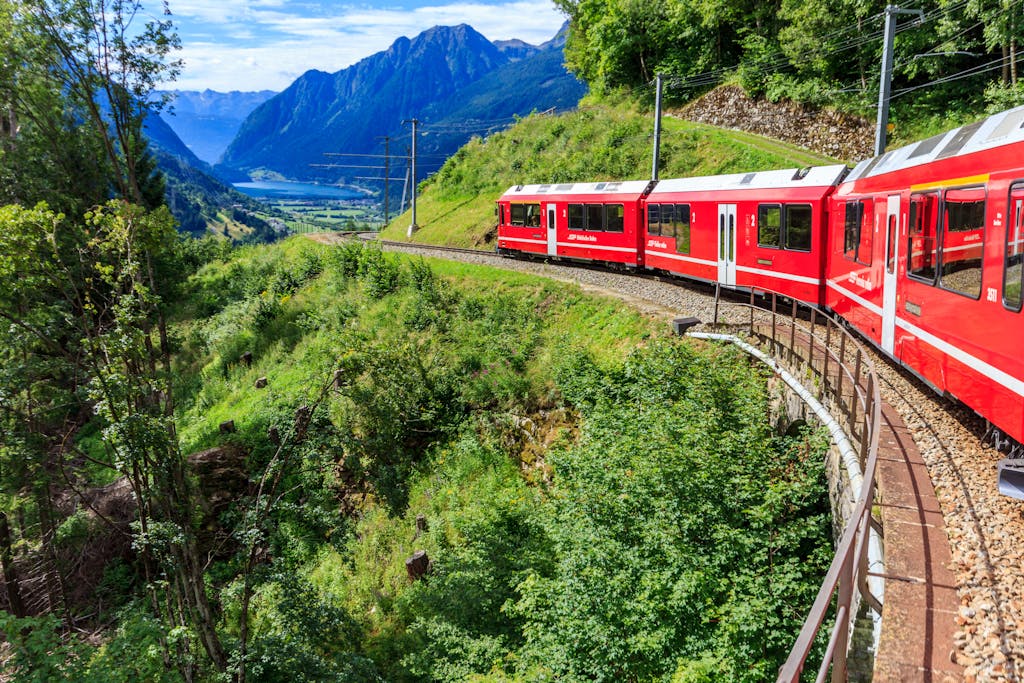 Bernina Express train curves through the stunning Swiss Alps, offering breathtaking views of mountains and valleys.
