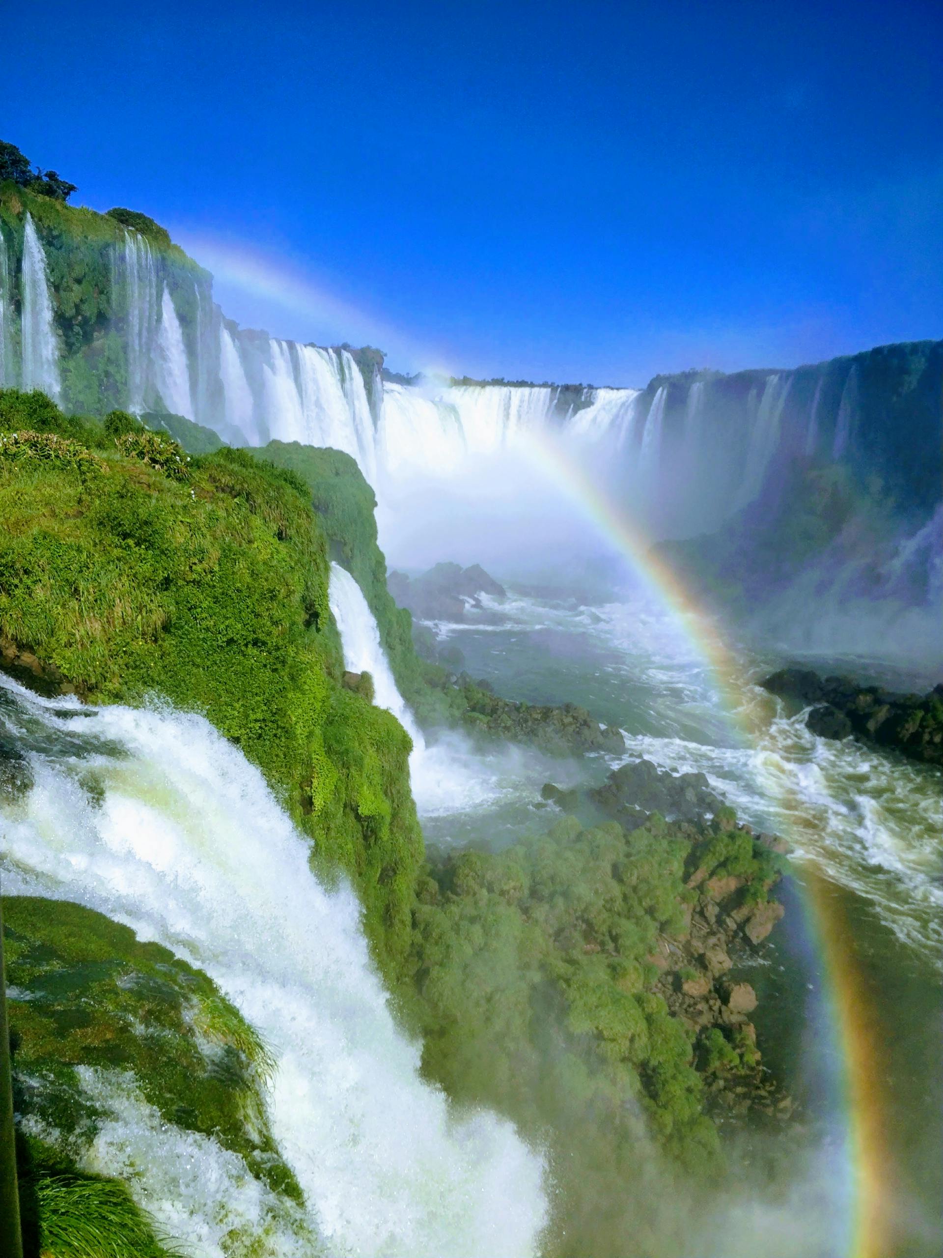 Breathtaking view of Iguazu Falls in Paraguay with vibrant rainbow and lush greenery.