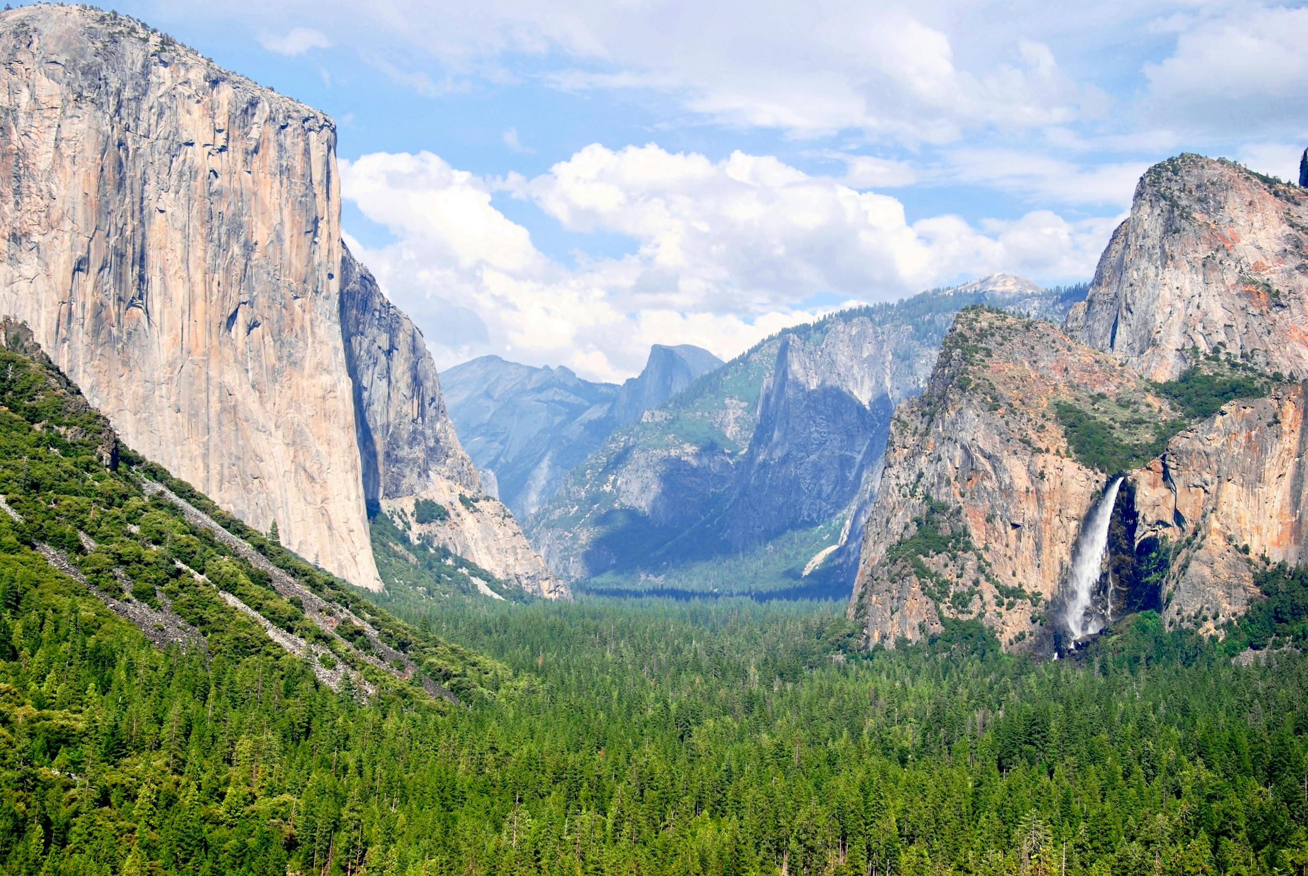 Breathtaking view of Yosemite Valley showcasing impressive cliffs and waterfalls in a lush green landscape.