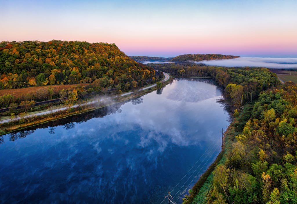Captivating aerial shot of a scenic river bend in Wacouta, MN at sunrise, showcasing fall foliage.