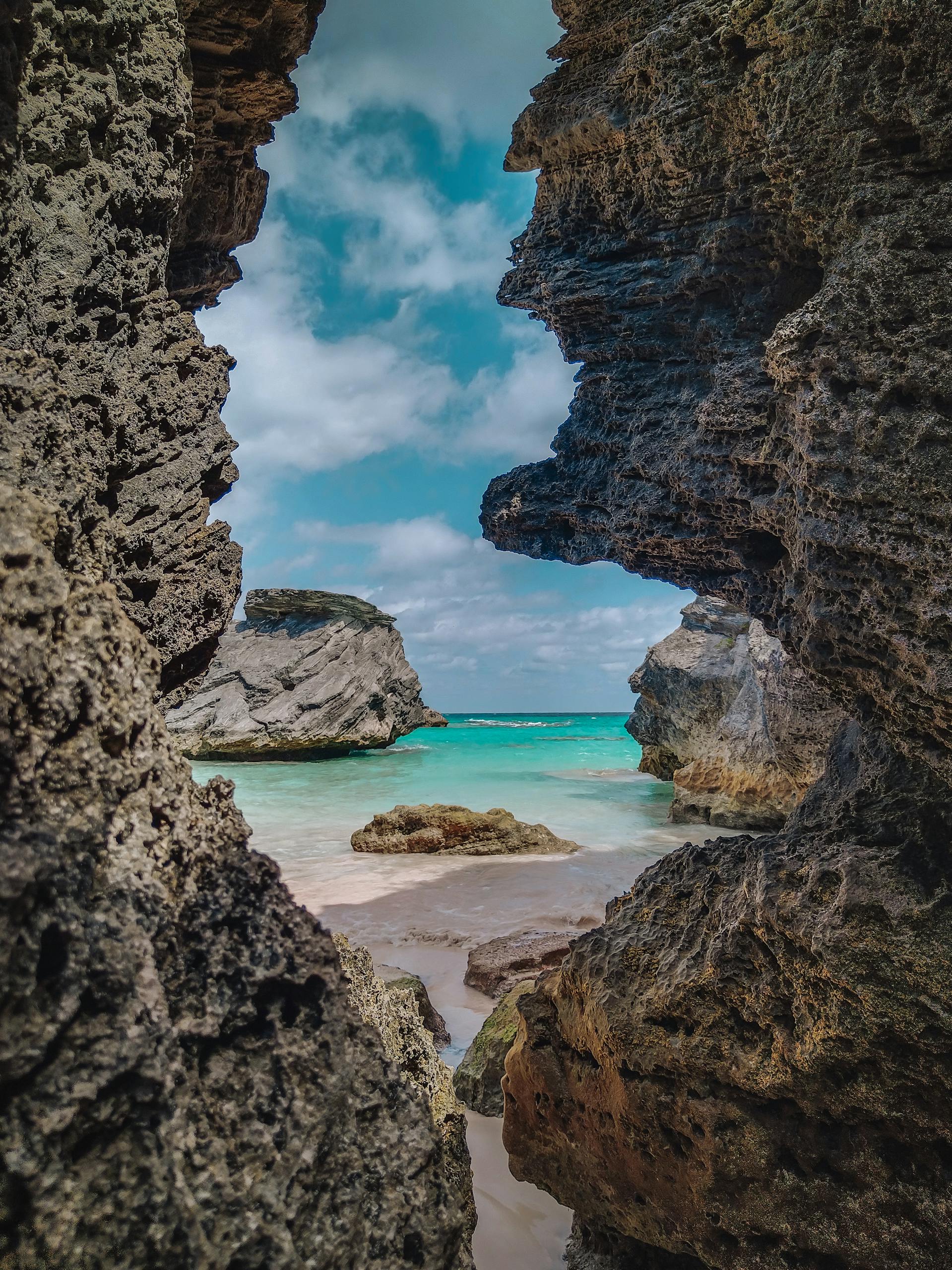 Explore a stunning coastal view through eroded rocks with turquoise waters and a bright sky.