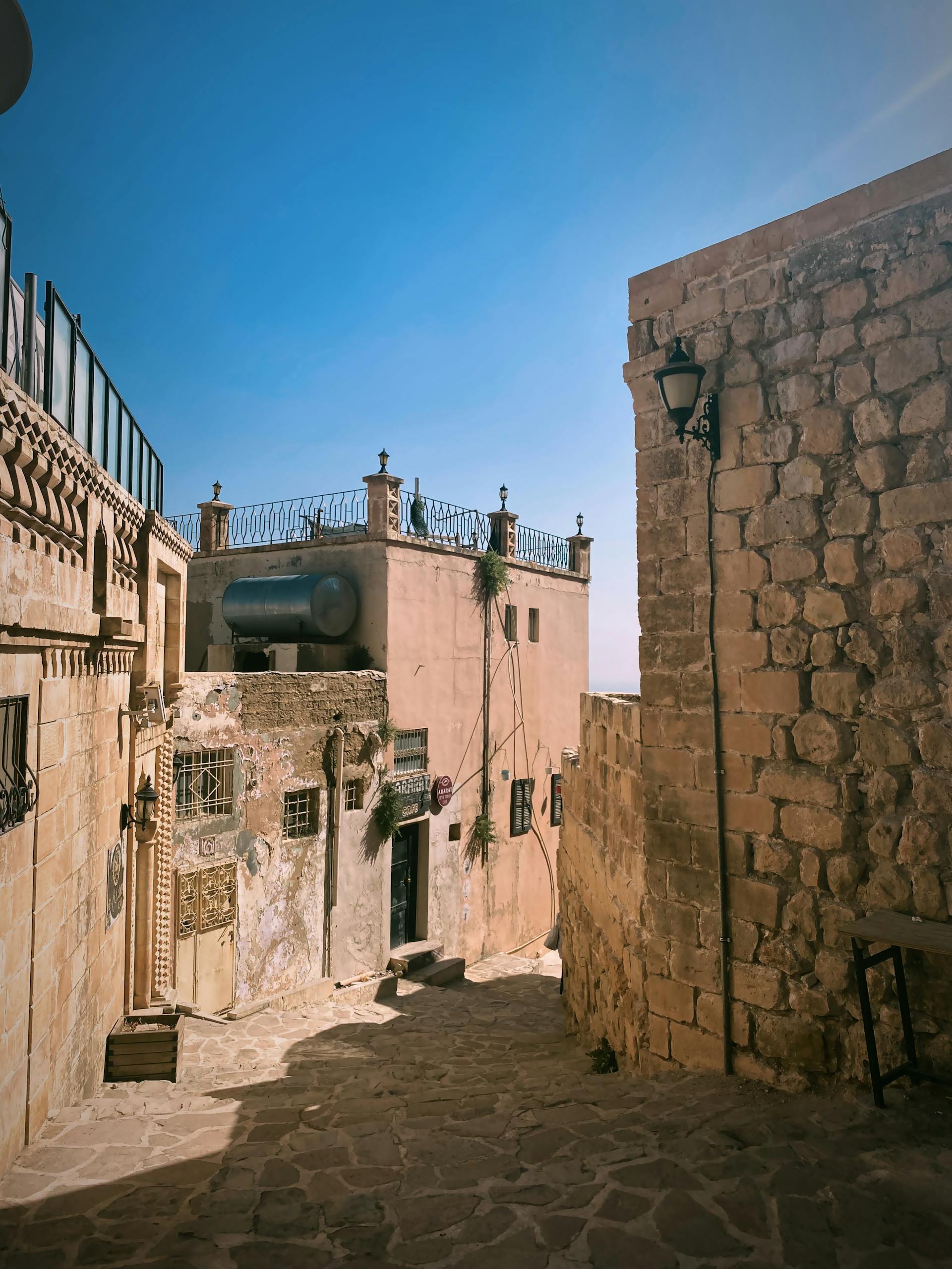 Explore a sunlit stone alleyway in an ancient Middle Eastern town. Perfect for travel inspiration.