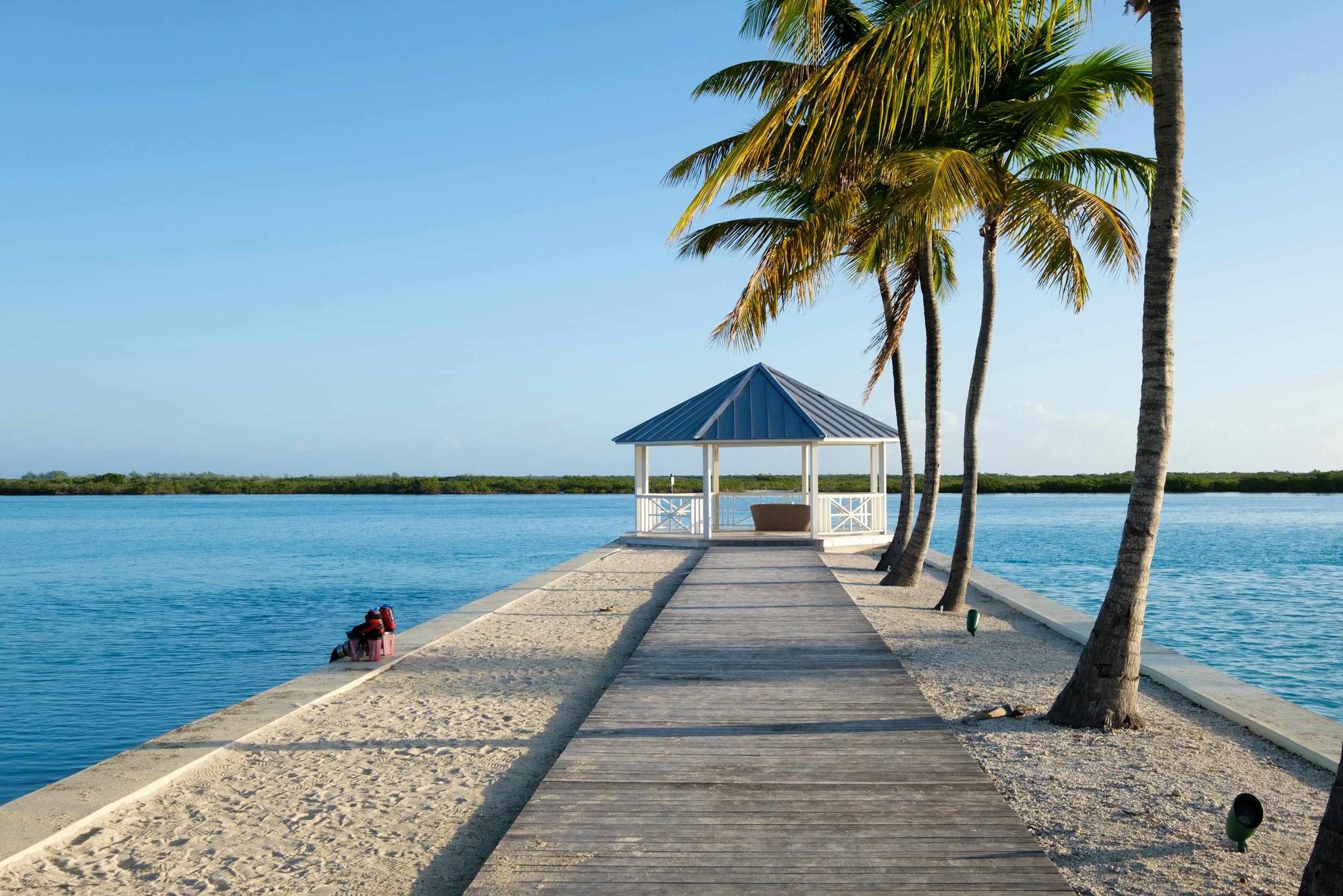 Idyllic tropical scene of a gazebo by the sea with palm trees and bright summer light.