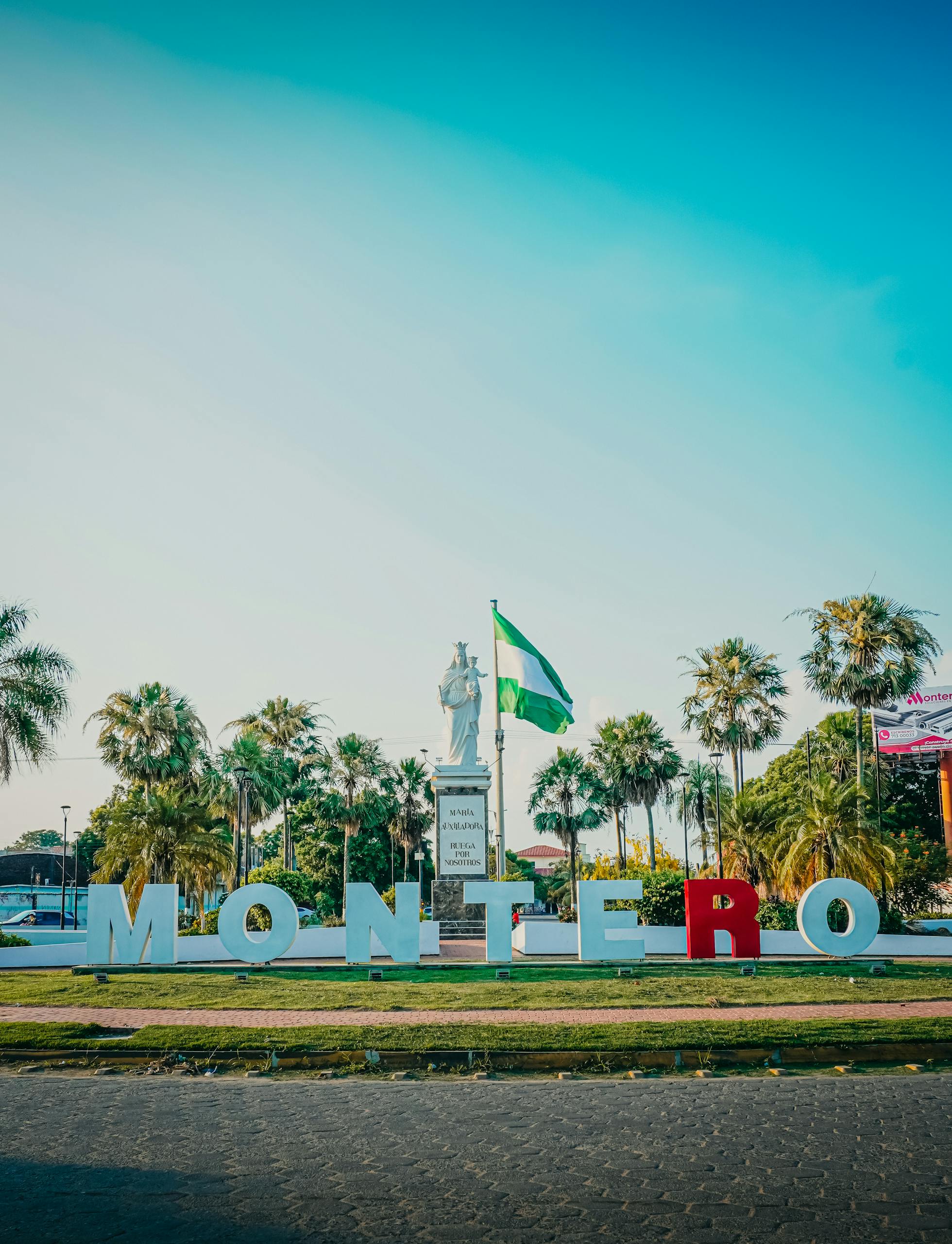 Montero city sign with landmark statue and Bolivian flag in Santa Cruz, Bolivia.