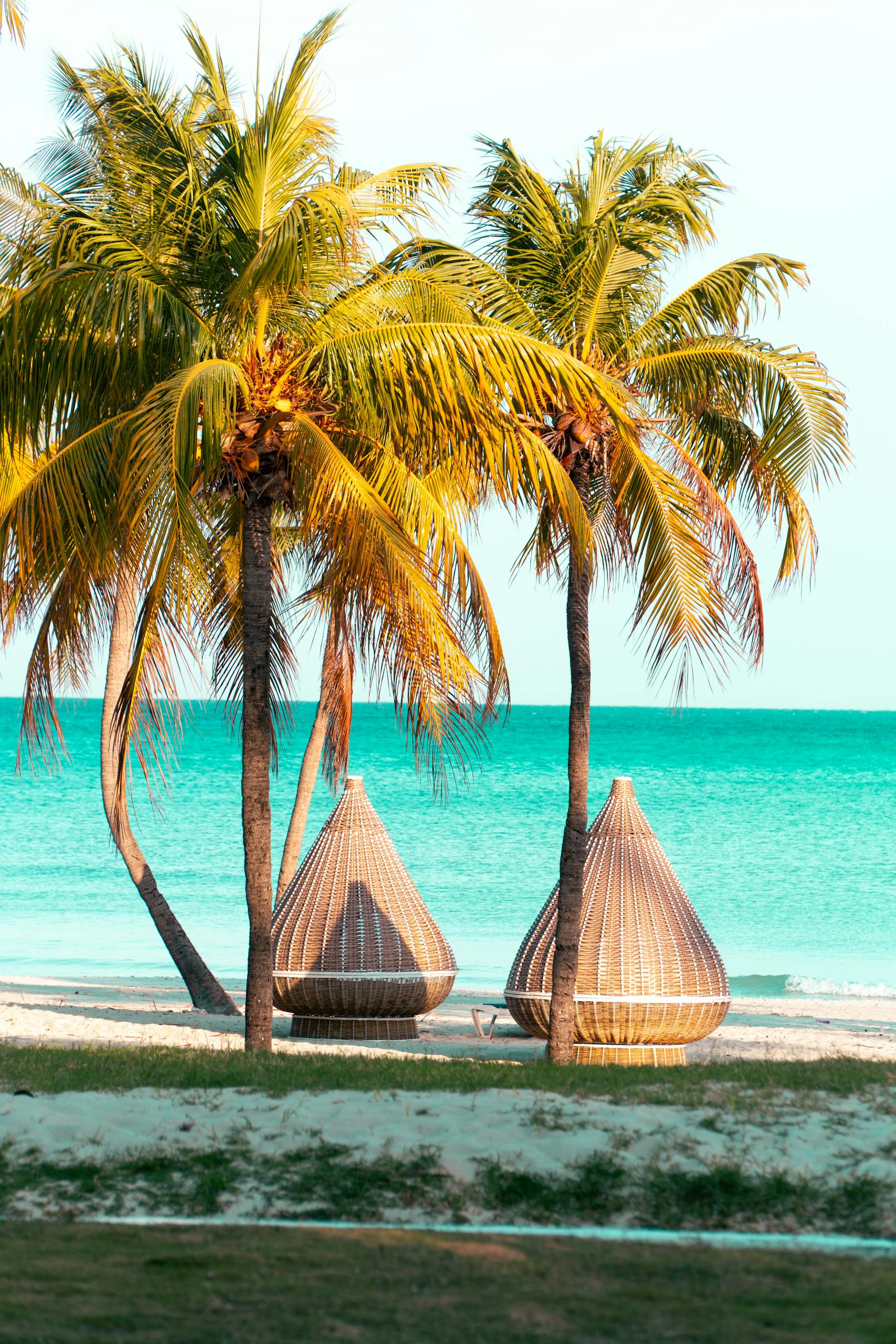 Serene tropical beach in Varadero, Cuba with palm trees and beach baskets.