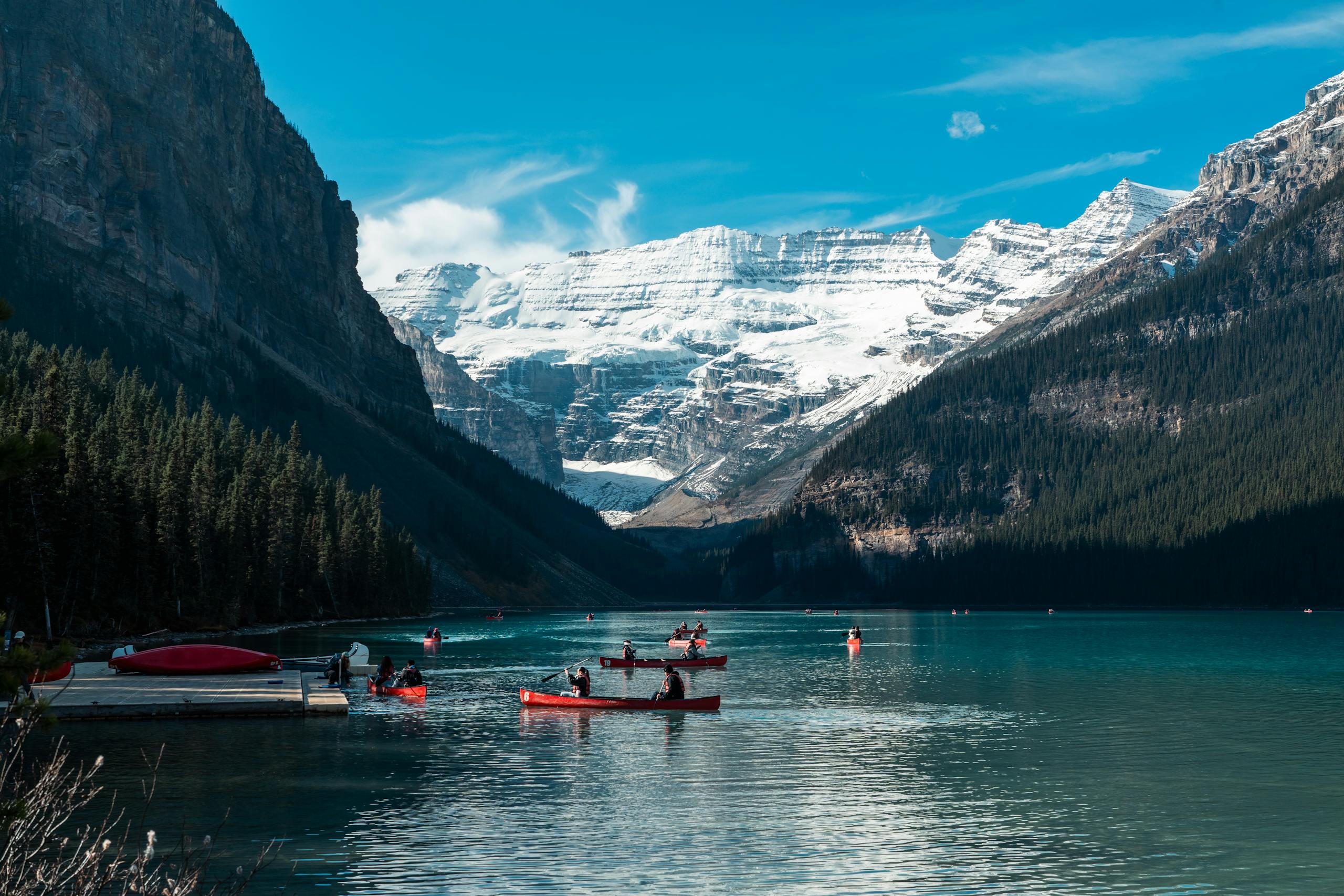Serene view of canoes on Lake Louise surrounded by snow-capped mountains in Banff National Park, Alberta.