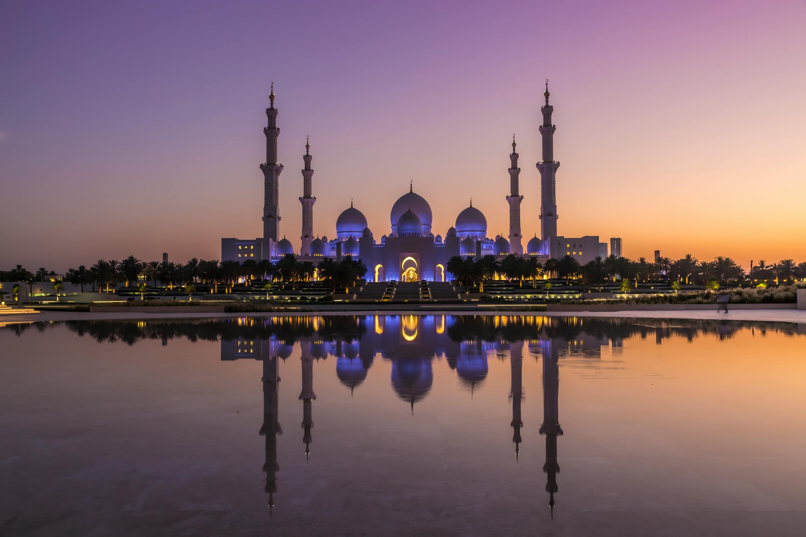 Stunning view of Sheikh Zayed Grand Mosque reflecting in water at sunset in Abu Dhabi.