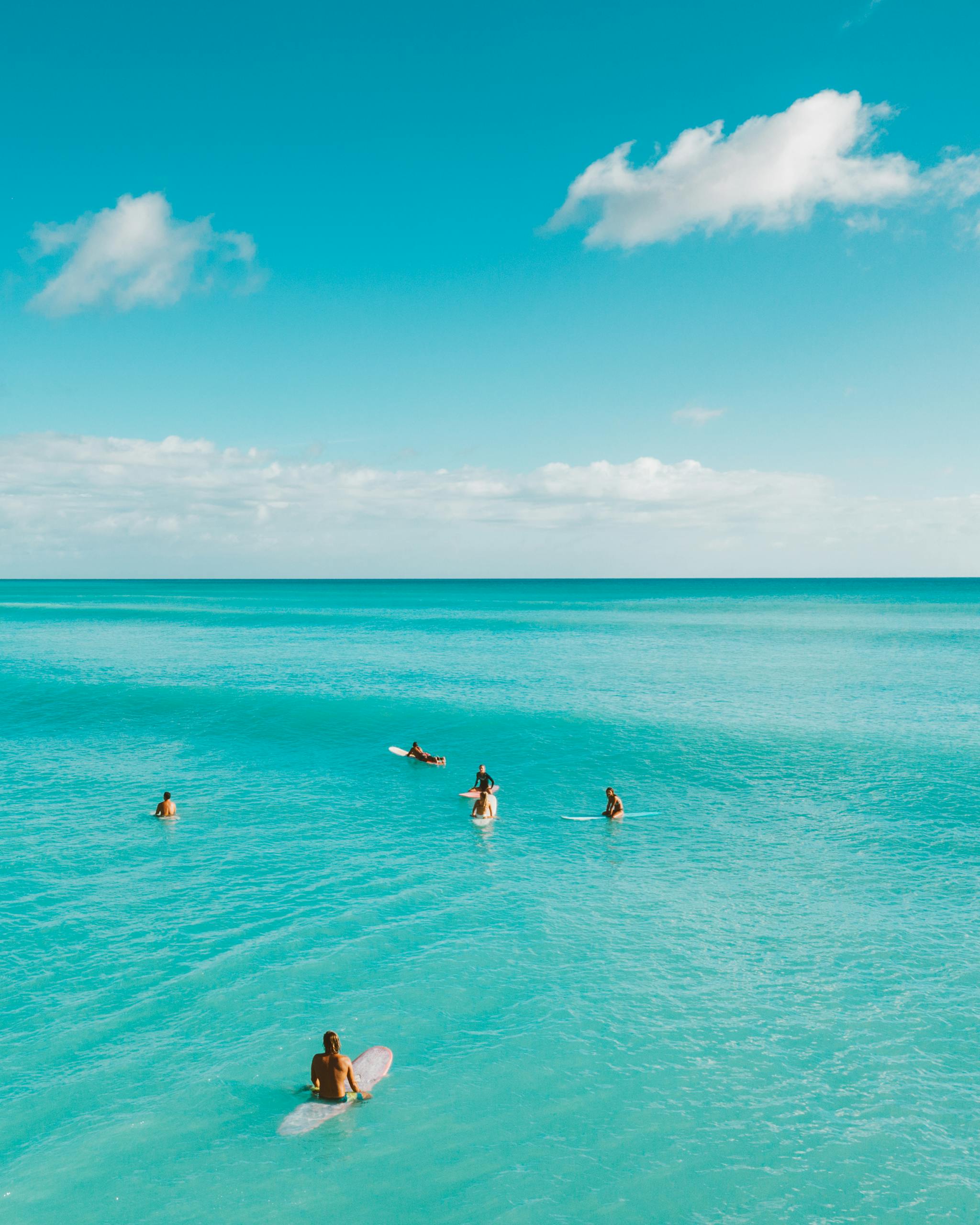 Surfers enjoying the turquoise sea on a bright summer day, perfect for adventure and fun.